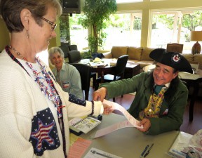 Poll worker Scott Ferguson hands a ballot to Sue Wameling as Joann Heller looks on at Scenic Hills.