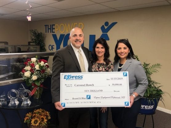 Carousel Ranch Executive Director Denise Redmond (center) accepts a $10,000 donation from Express Employment Professionals. Yvonne Rockwell, owner of the Santa Clarita office, and Roy Rockwell made the presentation as part of the company’s "Brand It Blue" initiative. Courtesy photo.