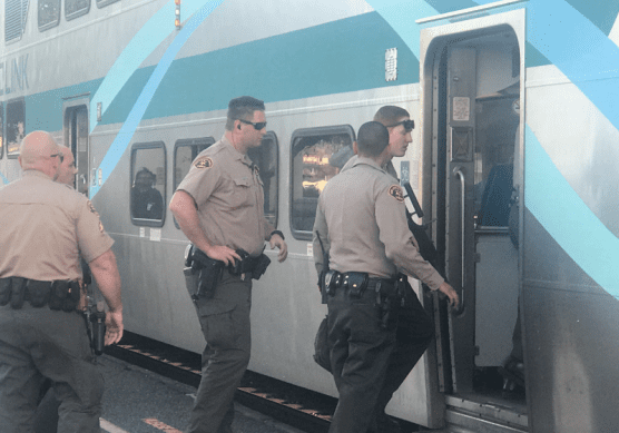Deputies board a Metrolink train to detain a suspect believed to have brandished a knife at train employees on Friday. | Photo: Jim Holt / The Signal.